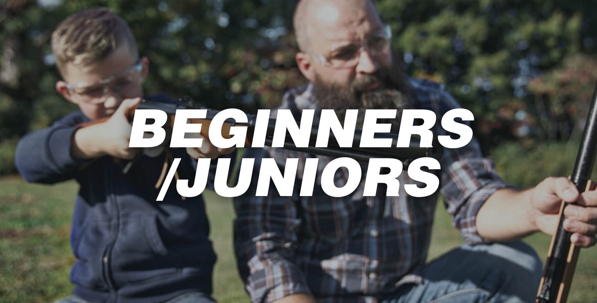 A bearded adult and a junior wearing safety goggles practise shooting outdoors. Large text over the image reads &ldquo;BEGINNERS / JUNIORS.&rdquo;.